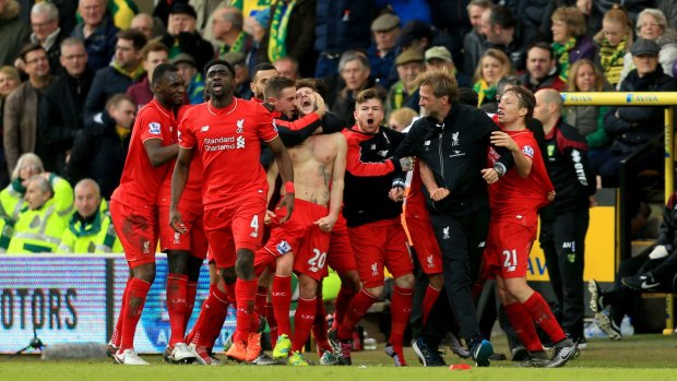 Leaving it late: Liverpool players and staff celebrate after Adam Lallana (centre) scored an injury-time winner against Norwich.