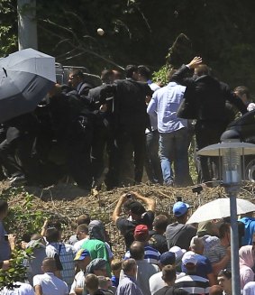A projectile is clearly visible as bodyguards use an umbrella to protect Aleksandar Vucic  at the commemoration of the Srebrenica massacre.