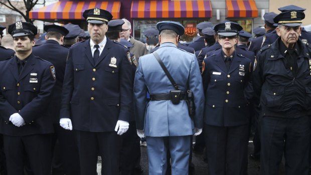 Silent snub: Some police officers turn their backs as New York City Mayor Bill de Blasio speaks on a monitor outside the funeral for policeman Wenjian Liu in Brooklyn on Sunday.