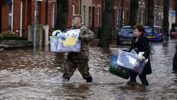 A member of the armed forces helps a resident move their belongings through the floods in Carlisle, north west England.