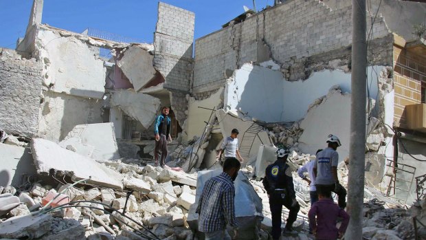 Members of the Syrian Civil Defence group (White Helmets) and residents inspect damaged buildings in Aleppo, on Sunday.