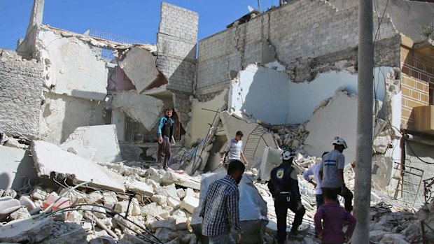 Members of the Syrian Civil Defence group (White Helmets) and residents inspect damaged buildings in Aleppo, on Sunday.