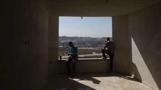 Palestinian workers look out from a building under construction in Kufr Aqab.
