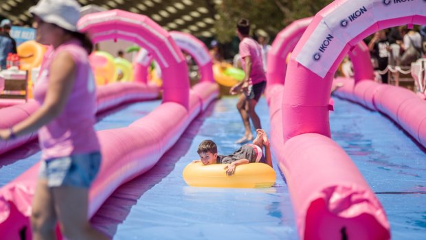 Locals and travellers escape Melbourne's summer at Federation Square's temporary waterslide. 