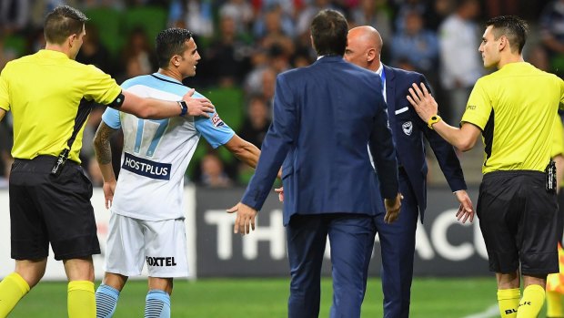 The referee intervenes between former teammates Tim Cahill and Kevin Muscat on Tuesday night.