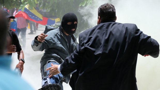 A masked man kicks at opposition lawmaker Franco Casella in a melee with supposed government supporters who tried to forced their way into the National Assembly on Wednesday.