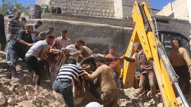 In this file photo from a June attack, civil defense workers and Syrian citizens rescue people after airstrikes hit a market area in Idlib, Syria. 