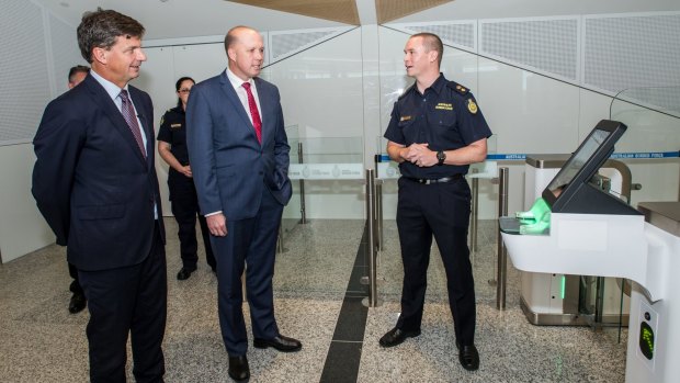 Ministers Angus Taylor and Peter Dutton check out one of the old SmartGates in the international departure lounge at Canberra Airport.