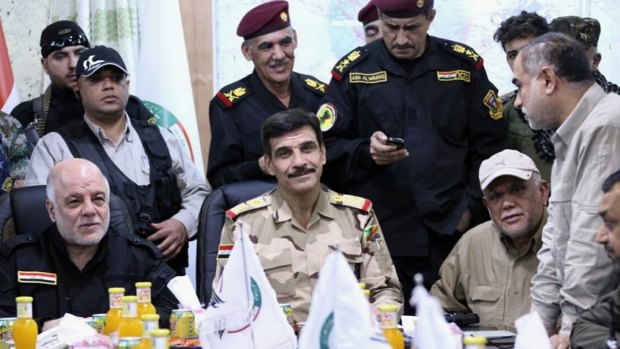 Iraqi Prime Minister Haider al-Abadi, seated in black, meets officers at the Fallujah Operation command centre on Monday. Also seated in a beige baseball cap is Hadi al-Amiri, head of the Iranian-funded Shiite militia known as the Badr Organisation.