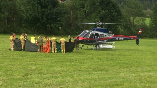 Rescue workers stand next to a police helicopter in Krimml in the Austrian province of Salzburg, Sunday.