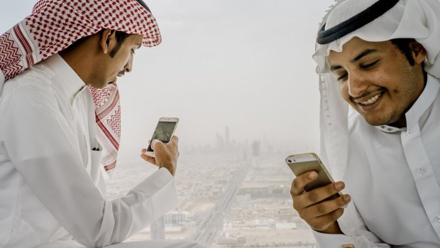 Men use their phones on the skybridge of Kingdom Tower in Riyadh, Saudi Arabia.