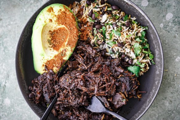 Mexican beef cheek stew with beans, rice and avocado sprinkled with some spice.