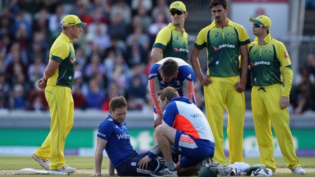 Morgan receives treatment after being struck on the helmet by a short ball from Mitchell Starc.