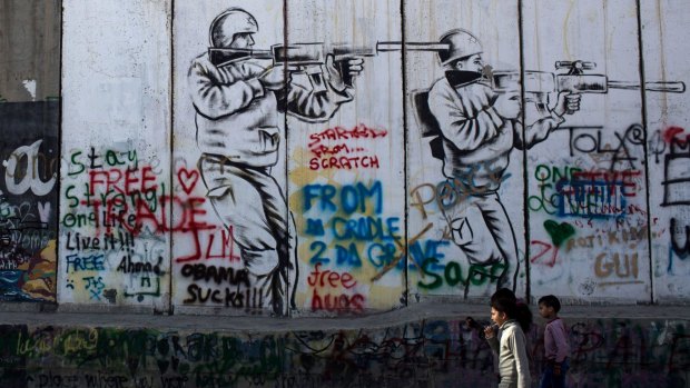 Children walk past graffiti painted on the Palestinian side of the separation wall in Bethlehem, in the Israeli-occupied West Bank. 