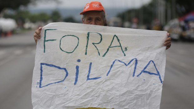 A woman holds a message that reads in Portuguese "Get out Dilma" during a protest demanding the impeachment of Brazil's President Dilma Rousseff in Brasilia.