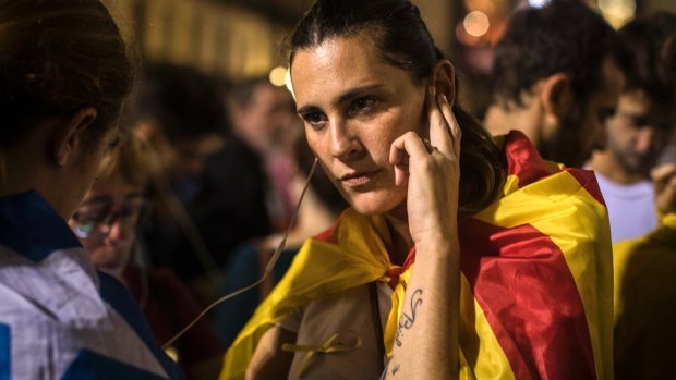 A girl listens on her phone to Catalan President Carles Puigdemont's speech outside the Palau Generalitat in Barcelona.