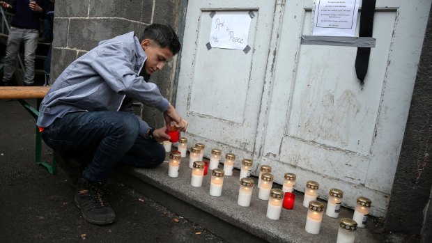 A young man lights a candle at a makeshift memorial to a young Syrian man believed to have died while waiting to receive government benefits.