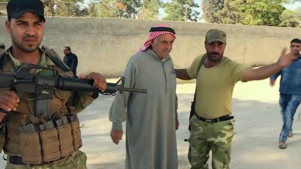 Turkish-backed Syrian opposition forces allow a man to pass after being searched in Dabiq, Syria.