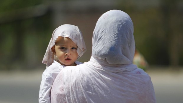 A mother and a child with his head covered with a wet towel to protect them from the scorching heatwave last week in India that set a record temperature in India of 51 degrees.