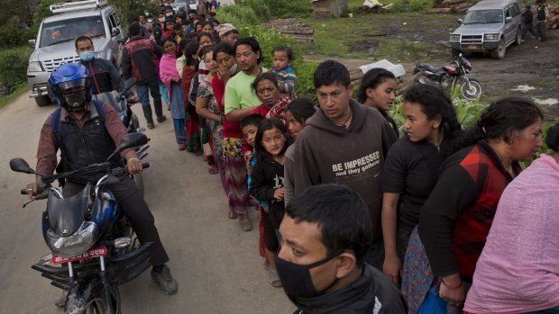 Nepalese villagers line up to receive food being distributed in Sakhu, on the outskirts of Kathmandu, on Wednesday.
