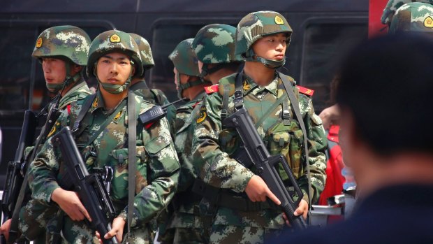 Violence: Paramilitary policemen stand guard near the exit of the South Railway Station, where three people were killed and 79 wounded in a bomb and knife attack in Xinjiang last year.