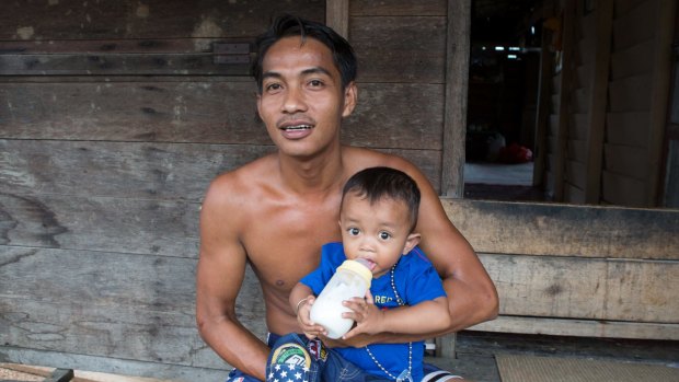 Tengku Antonia bottle feeds his son Tengku Ayuan Kuadi outside his home in Pelalawan village, in Riau province.