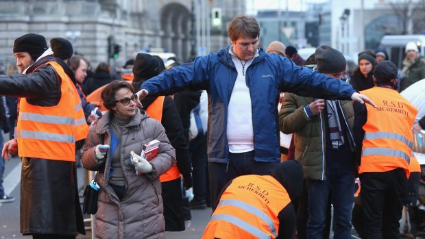 Security officers frisk New Year's Eve revellers in Berlin.