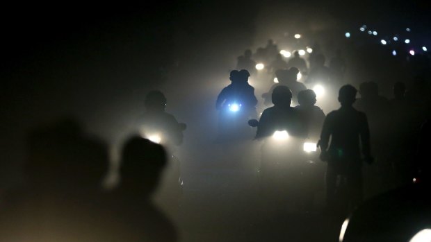 Indian motorists ride past a thick blanket of smog and dust on the outskirts of Delhi, India. 