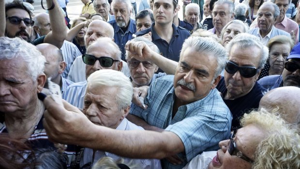 Pensioners line up outside a bank branch in Athens. ATMs attract queues long into the evening.