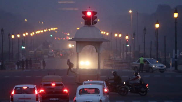 Traffic stands at a junction on King's Way boulevard while shrouded in smog at night in Delhi, India.