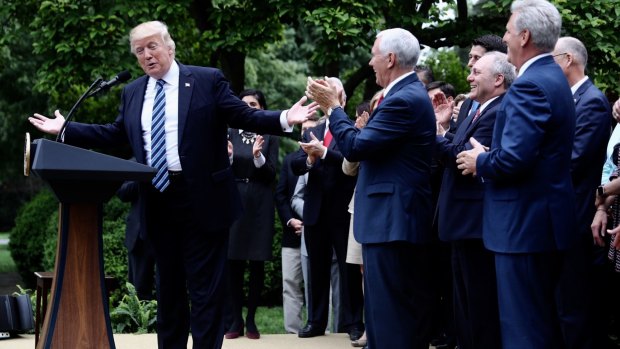 US President Donald Trump celebrates with Vice President Mike Pence and other Republicans after the House voted to pass their health-care bill, repealing Obamacare. 