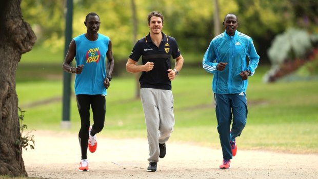 Not quite AFL style: David Rudisha, left, with the Hawks’ Isaac Smith and Sammy Tangui.
