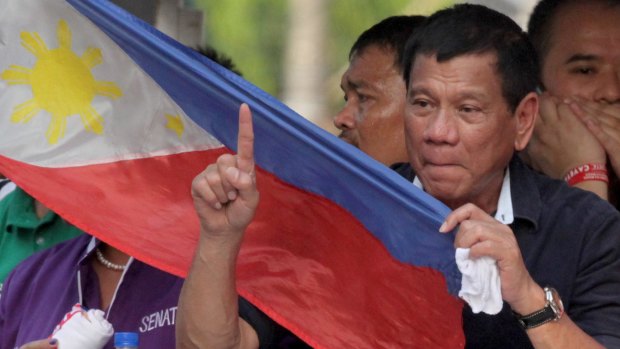 Presidential candidate Mayor Rodrigo Duterte holds a Philippines flag as his campaign motorcade makes its way through the streets of Malabon, Philippines.