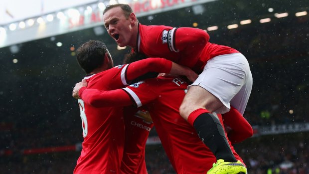 Marouane Fellaini of Manchester United is mobbed  by captain Wayne Rooney and their teammates after scoring against City on Sunday. 
