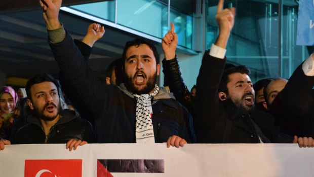 Holding a banner with a Turkish, left and a Palestinian flag, right, protesters chant anti-US slogans during a demonstration near the US embassy in Ankara, Turkey.