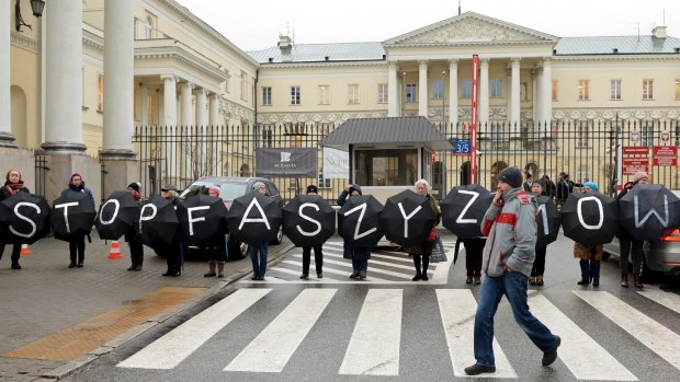 A man walks past a group of civic rights activists with umbrellas forming a slogan Stop Fascism, as they protest what they saw as the authorities' failure to respond to the behaviour of the nationalists during the Independence March that took place on November 11, in Warsaw, Poland.