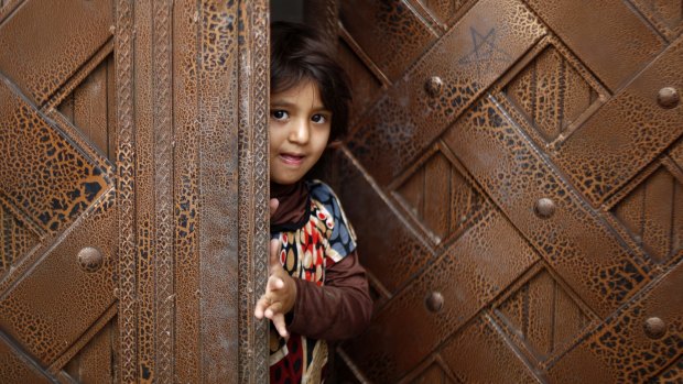 A Yemeni child stands at a door as she waits to receive a polio vaccination during a house-to-house immunisation campaign in Sanaa.