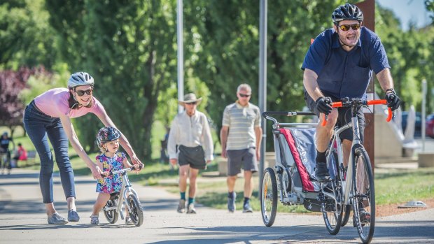 Pedal Power communications manager Anne Treasure with husband Glen Fuller and daughter Aurora enjoy cycling together around Lake Burley Griffin.