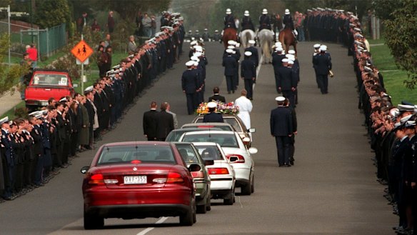 Members of the police salute Gary Silk as the hearse carrying his body leaves the police academy on August 20, 1998.