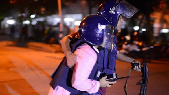 Bangladeshi police take cover near a restaurant that has been attacked by unidentified gunmen.