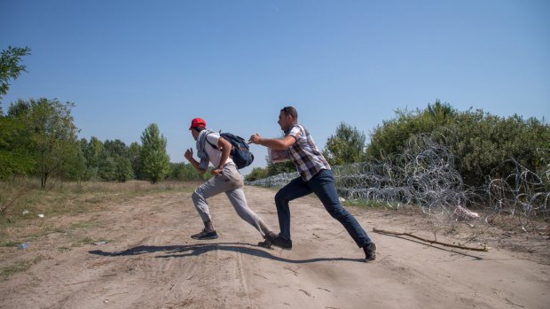 Migrants dash to the woods after scrambling through the fence on the Serbia-Hungary border on Sunday.  
