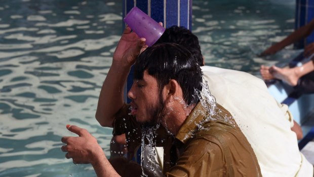 A Pakistani man cools down with water at a mosque.