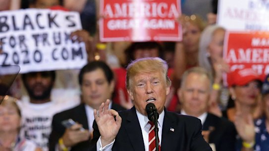 President Donald Trump speaks at a rally at the Phoenix Convention Centre.- a 'Blacks for Truth' sign in the background.