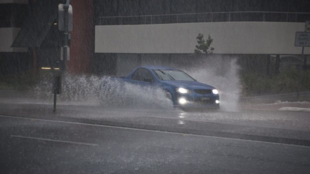 A car drives through water over the road after heavy rain.