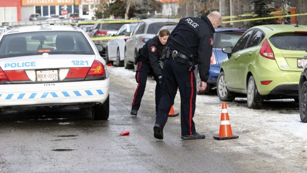 Calgary police place crime scene markers on a street were seven people were shot in a New Year's house party in Killarney.