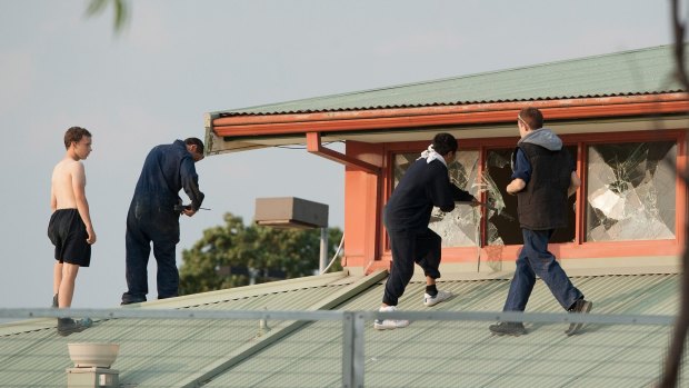 Six youths are seen protesting on the roof of the Melbourne Youth Justice Centre in Parkville.