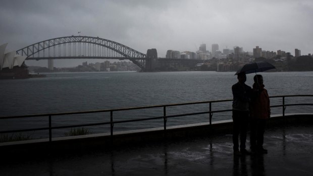Tourists huddle under an umbrella as rain hits Sydney on Wednesday.