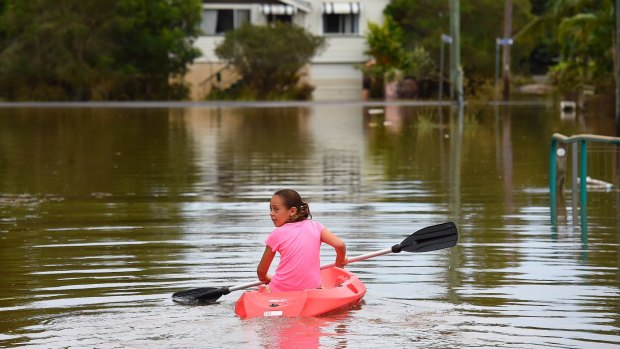 Maleah Jones, 8 years old, canoes up flooded Bright street to her home in Lismore.