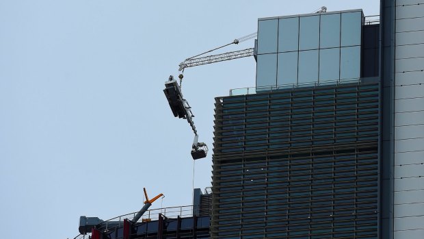The damaged crane hangs from the 51st floor of the highest tower at Barangaroo in the Sydney CBD.
