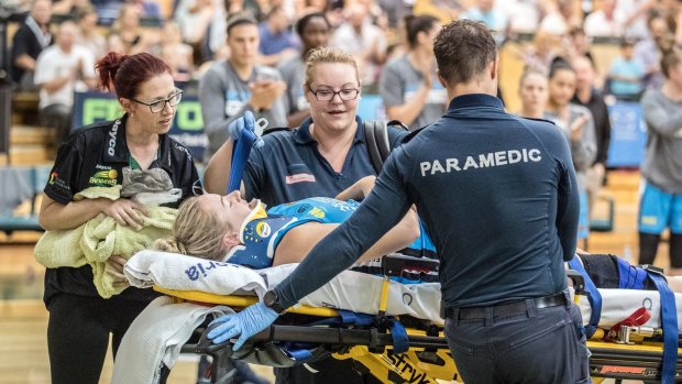 Canberra's Rachel Jarry, neck in a brace, is assisted from the Dandenong court by paramedics. 